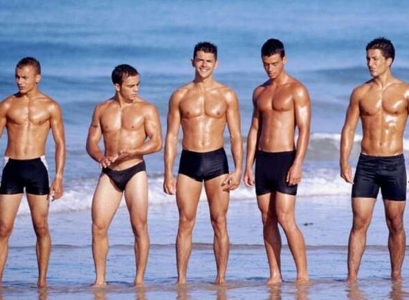 vīrieši pludmalē ar palielinātiem gaiļiem